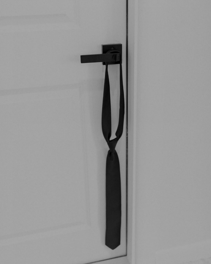 Corbata negra colgada de una puerta